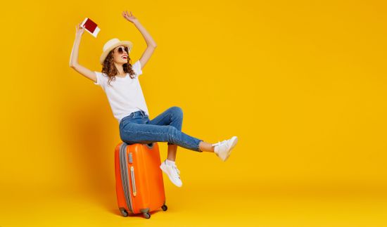 Frau sitzt auf Koffer und reist in Urlaub